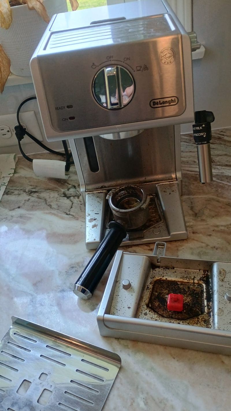 Espresso machine before cleaning, drip tray full of coffee grounds