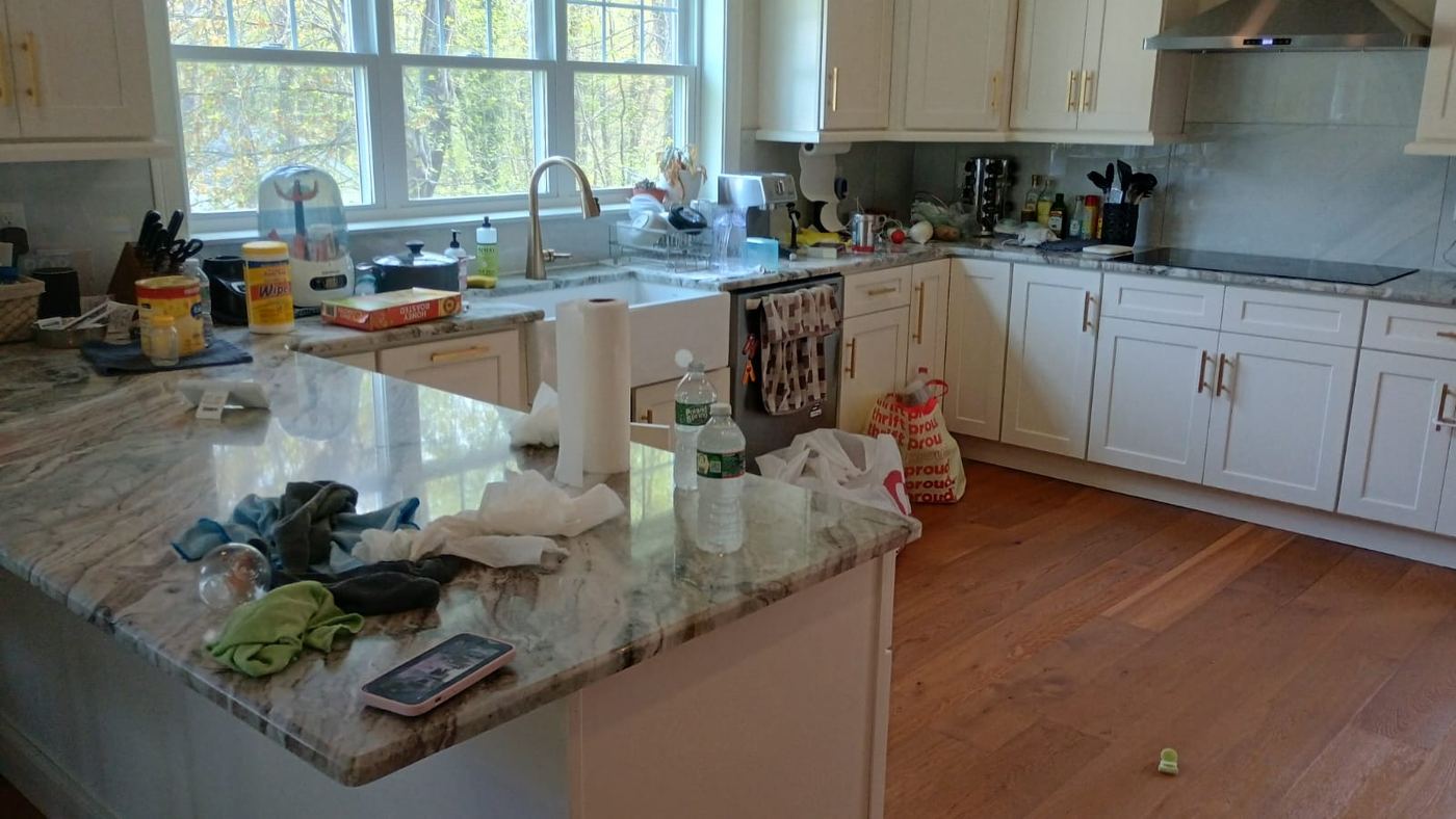 Kitchen before cleaning, counters covered with clutter